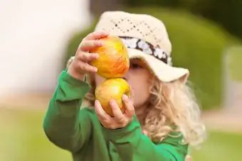 Jeune fille tenant deux pommes bio.