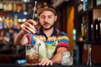 barman en remuant un cocktail dans un verre