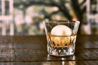 Brúsený pohár obsahuje whisky a okrúhly ľad
