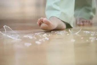Orang berjalan tanpa kaki dengan kaca pecah di atas lantai