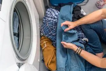 امرأة تضيف مزيل البقع إلى الملابس قبل غسلها