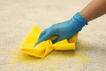 Kvinne i blå hansker som renser teppe
