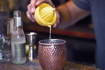 Barman adicionando limão espremido ao coquetel