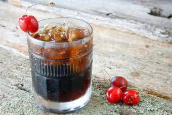 Um copo de Joe Collins e cubos de gelo com cerejas frescas maduras como guarnição