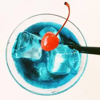 Kirsche im blauen Cocktail vor weißem Hintergrund