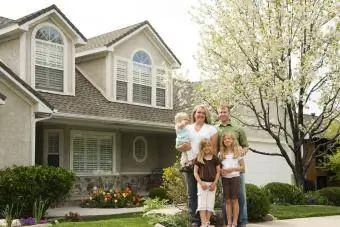 Familia de cinco miembros en casa frente a un árbol de flores blancas