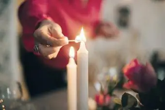 Femme mature allumant une bougie sur une table à manger