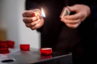 رجل يشعل الشموع بأعواد الثقاب ويضيء شمعة