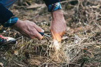 Un bărbat face un foc cu o cremene