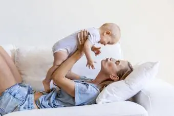 Moeder ligt op de bank en houdt haar babymeisje vast