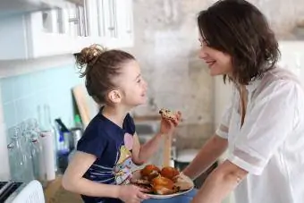 Bir kız ve annesi mutfakta kurabiye yiyor