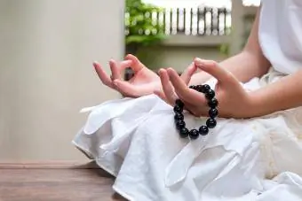 Meditasyon yaparken kızın elinde siyah boncuklu bileklik