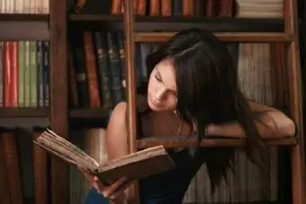 Ung kvinna som läser på det antika biblioteket