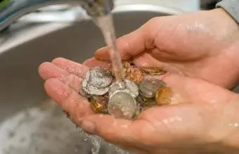 Lavar monedas en el fregadero con agua.