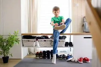 kapının önünde ayakkabısını giyen çocuk