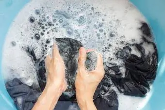 Femeie care spală hainele cu mâna