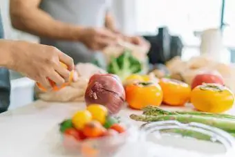 Gambar dekat tangan wanita semasa menyediakan makanan vegan di rumah