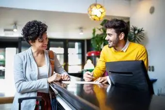 Jonge zakenvrouw arriveert bij het hotel en vult registratiedocumenten in bij de receptie