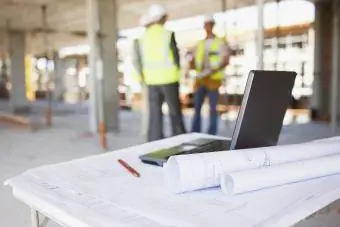 Stavební dělníci za plány a notebook na staveništi