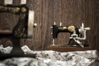 Pequeña máquina de coser decorativa nostálgica sobre fondo de madera marrón
