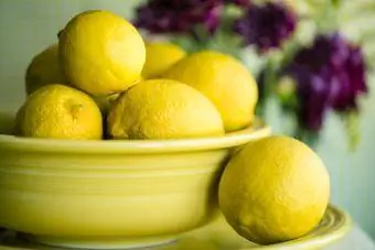 Limões em uma tigela no prato com flores atrás