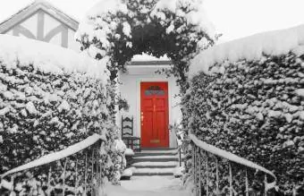 sniegots skats uz māju ar sarkanām durvīm