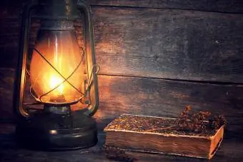 Beleuchtete antike Laterne mit altem Buch auf dem Tisch