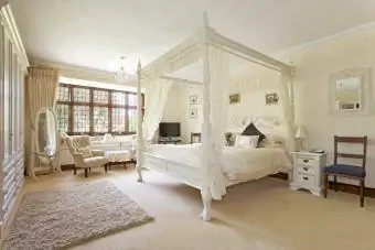 Büyük nötr renkli yatak odasında beyaz sayvanlı yatak