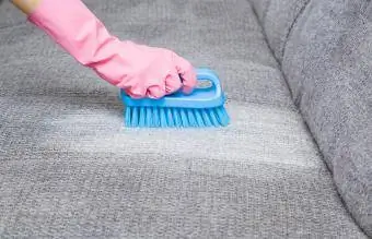 fjerning av flekker fra grå sofa med børste