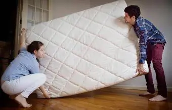 Couple portant un matelas dans la chambre