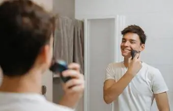 Мальчик-подросток бреется перед зеркалом