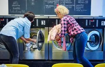 mulheres inserindo roupa em máquinas de lavar