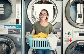 Giovane donna in una lavanderia automatica