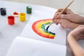 ידיו של ילד בידיו של מבוגר לומדות לצייר קשת בענן
