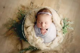 Menina recém-nascida enrolada em uma cesta de adereços