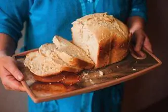 Mani che tengono il vassoio di pane fresco