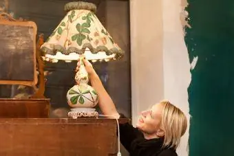 kvinna upptäcker antik vintage lampa på loppmarknad