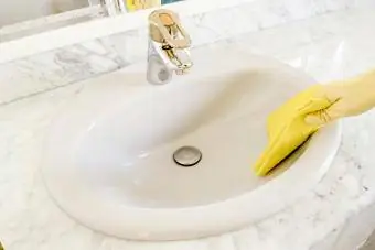 Porselen lavaboyu sarı eldivenlerle temizleme