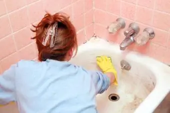 Mujer fregando bañera sucia
