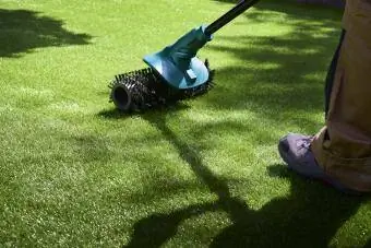 Arbetaren använder elektrisk borste för att rengöra högen av falskt gräs
