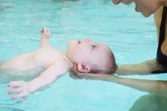 Mutter bringt Kleinkind bei, wie man im Schwimmbad schwimmt
