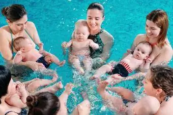 กลุ่มคุณแม่และลูกเล็กๆ ในชั้นเรียนว่ายน้ำสำหรับเด็ก