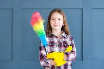 Linda chica con guantes de goma amarillos y plumero arcoíris