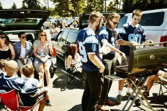 Amigos fazendo churrasco durante festa no estacionamento do estádio de futebol