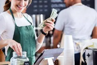 Barista saca dinero del tarro de propinas