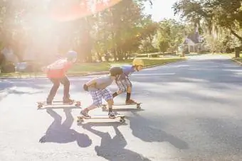 Amigos adolescentes haciendo longboard en un barrio suburbano