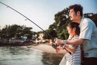 Keluarga muda memancing bersama-sama dengan riang di jeti
