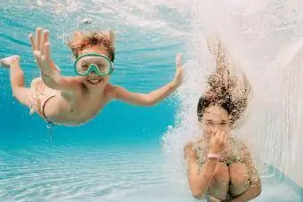 Meisie en seuntjie onder water in swembad