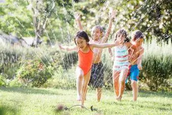 Bambini che corrono attraverso l'irrigatore d'acqua