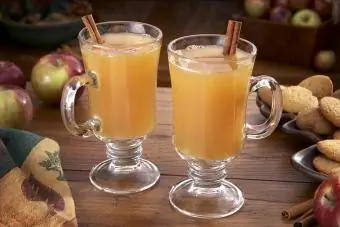 Cidre chaud fumant sur une table avec des pommes et des biscuits au gingembre